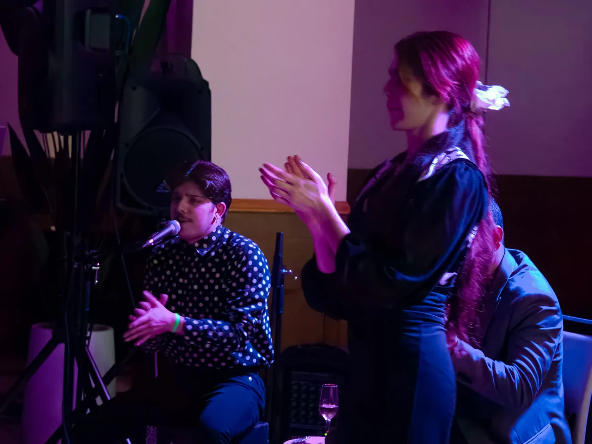 El cantaor canta al micrófono mientras la bailaora toca las palmas a su lado